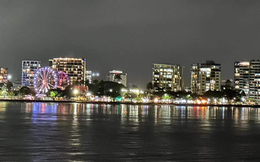 The lit waterfront of Cairns at night seen from the water