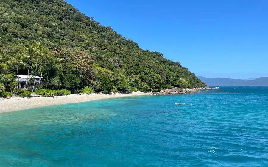 A turquoise bay with a sandy beach under a forested hill on Fitzroy Island
